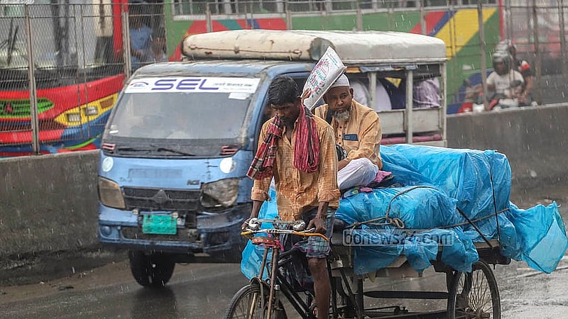 বৃষ্টির মধ্যে ভ্যানের মালামাল সুরক্ষায় পলিথিনে ঢেকে গন্তব্যে ছুটছেন এক ব্যক্তি। ছবি: আব্দুল্লাহ আল মমীন
