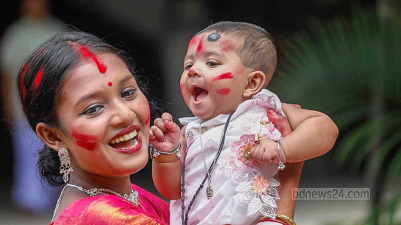 বিজয়া দশমীতে রোববার ঢাকেশ্বরী মন্দিরে সিঁদুর খেলায় শিশু কোলে এক নারী। ছবি: আব্দুল্লাহ আল মমীন