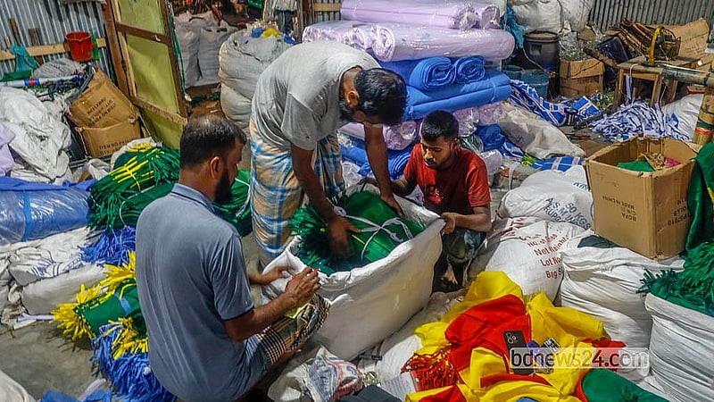 ঢাকার কদমতলী এলাকার একটি কারখানা থেকে ফুটবল বিশ্বকাপে অংশগ্রহণকারী বিভিন্ন দেশের পতাকা নিয়ে যাচ্ছেন দোকানিরা