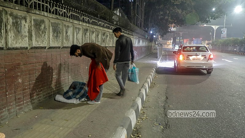 তীব্র শীতের মধ্যে রাজধানীর কাকরাইল এলাকায় ফুটপাতে কম্বল বিতরণ করতে দেখা যায় একজনকে।  ছবি: আব্দুল্লাহ আল মমীন
