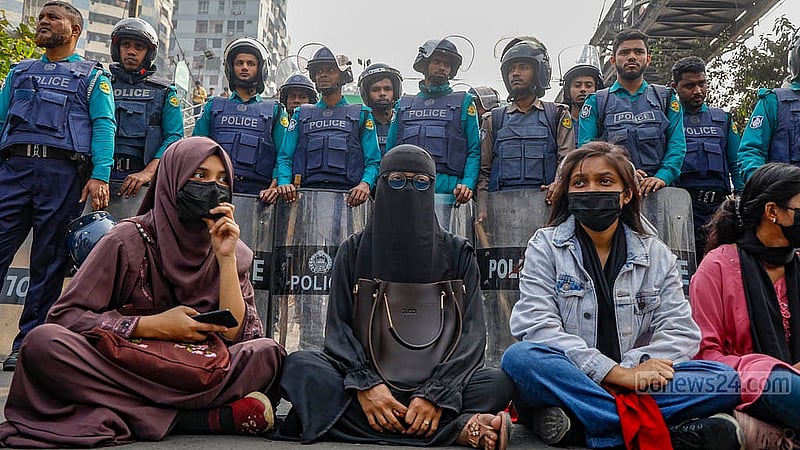 ঢাকা সেন্ট্রাল ইউনিভার্সিটি গঠনের চূড়ান্ত অধ্যাদেশ জারির দাবিতে বুধবার দুপুরে সায়েন্স ল্যাবরেটরি মোড় অবরোধ করে বসে পড়েন শিক্ষার্থীরা। পেছনে সারিবদ্ধভাবে দাঁড়িয়ে পুলিশ