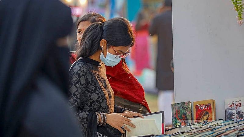 বইমেলার দ্বিতীয় দিন শুক্রবার সোহরাওয়ার্দী উদ্যানে বই দেখছেন এক তরুণী