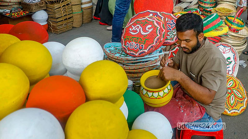 ঢাকা বিশ্ববিদ্যালয়ের দোয়েল চত্বরে কারুশিল্পের দোকানে মাটির হাঁড়িতে নকশা করছেন এক শিল্পী