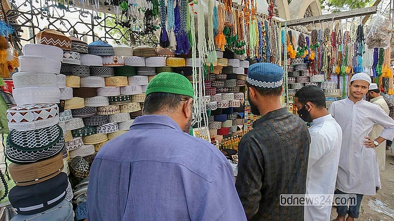 বায়তুল মোকারম জাতীয় মসজিদের সামনে দোকান থেকে টুপি কিনছে অনেকেই