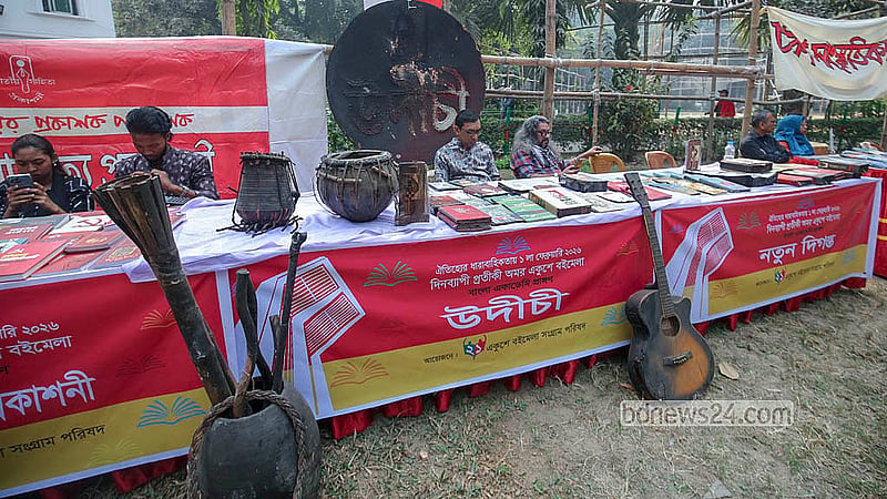 বাংলা একাডেমি প্রাঙ্গণে রোববার একদিনের প্রতীকী বইমেলায় একটি স্টলে সাজিয়ে রাখা হয় ‘মব’ হামলার শিকার উদীচীর ক্ষতিগ্রস্ত বাদ্যযন্ত্র।