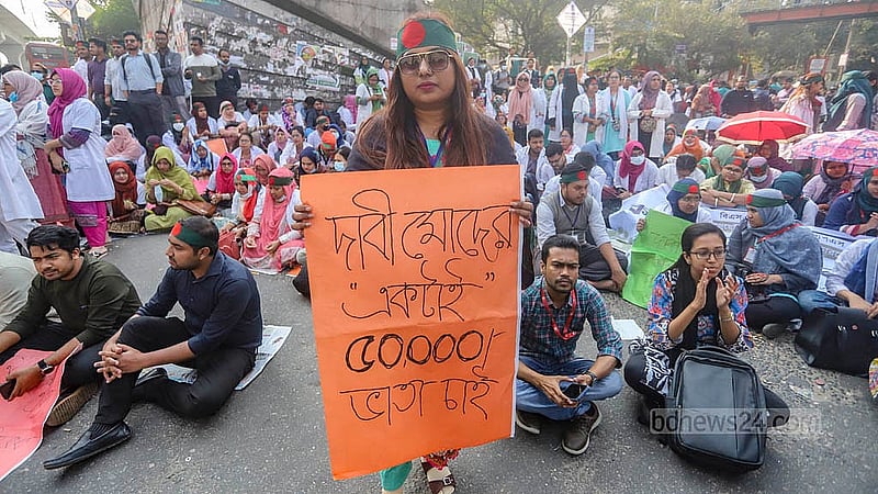 রাজধানীর শাহবাগ মোড় অবরোধ করে বিক্ষোভে প্ল্যাকার্ড হাতে ট্রেইনি চিকিৎসকরা। ছবি: আব্দুল্লাহ আল মমীন