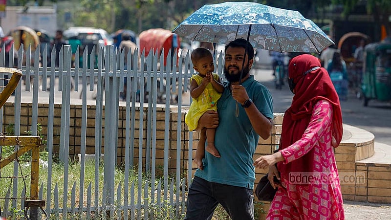 ঢাকা বিশ্ববিদ্যালয় এলাকায় সোমবার দুপুরে রোদ থেকে শিশুকে রেহাই দিতে ছাতা হাতে এক ব্যক্তি