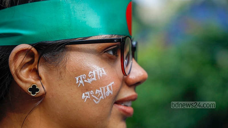 কপালে জাতীয় পতাকা বেঁধে, মুখে দাবিদাওয়া এঁকে শুক্রবার কাকরাইল মোড়ে আন্দোলনে যোগ দেন জগন্নাথ বিশ্ববিদ্যালয়ের এক শিক্ষার্থী। ছবি: মাহমুদ জামান অভি