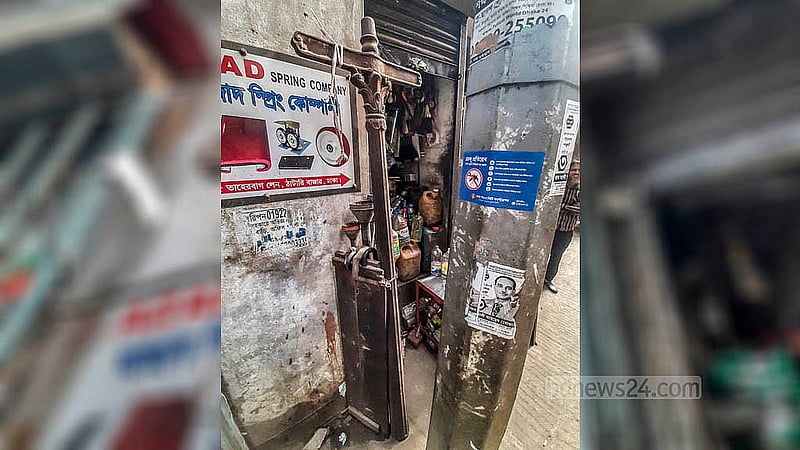 নবাবপুর তাহেরবাগ লেনে শত বছরের পুরনো বৈদ্যুতিক সড়কবাতির খুঁটিটি ঢাকা পড়ে গেছে এখনকার বৈদ্যুতিক খুঁটির আড়ালে।  ছবি: আব্দুল্লাহ আল মমীন