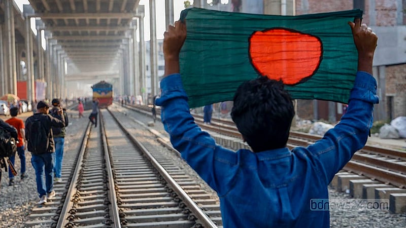 ঢাকার মহাখালী রেলক্রসিংয়ে রেললাইনের ওপর পতাকা নিয়ে ট্রেন থামানোর চেষ্টায় তিতুমীর কলেজের এক শিক্ষার্থী। ছবি: মাহমুদ জামান অভি