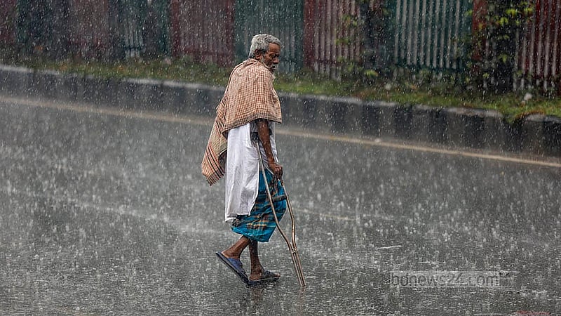 ঢাকার টেকনিক্যাল এলাকায় মঙ্গলবার দুপুরে ঝুম বৃষ্টির মধ্যে সড়ক পার হচ্ছেন এক ব্যক্তি। ছবি: মাহমুদ জামান অভি