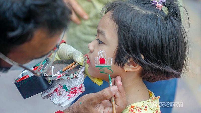 কেন্দ্রীয় শহীদ মিনারে ভাষা শহীদদের শ্রদ্ধা জানাতে আসা এক শিশুর গালে শহীদ মিনারের আলপনা এঁকে দিচ্ছেন একজন। ছবি: আব্দুল্লাহ আল মমীন