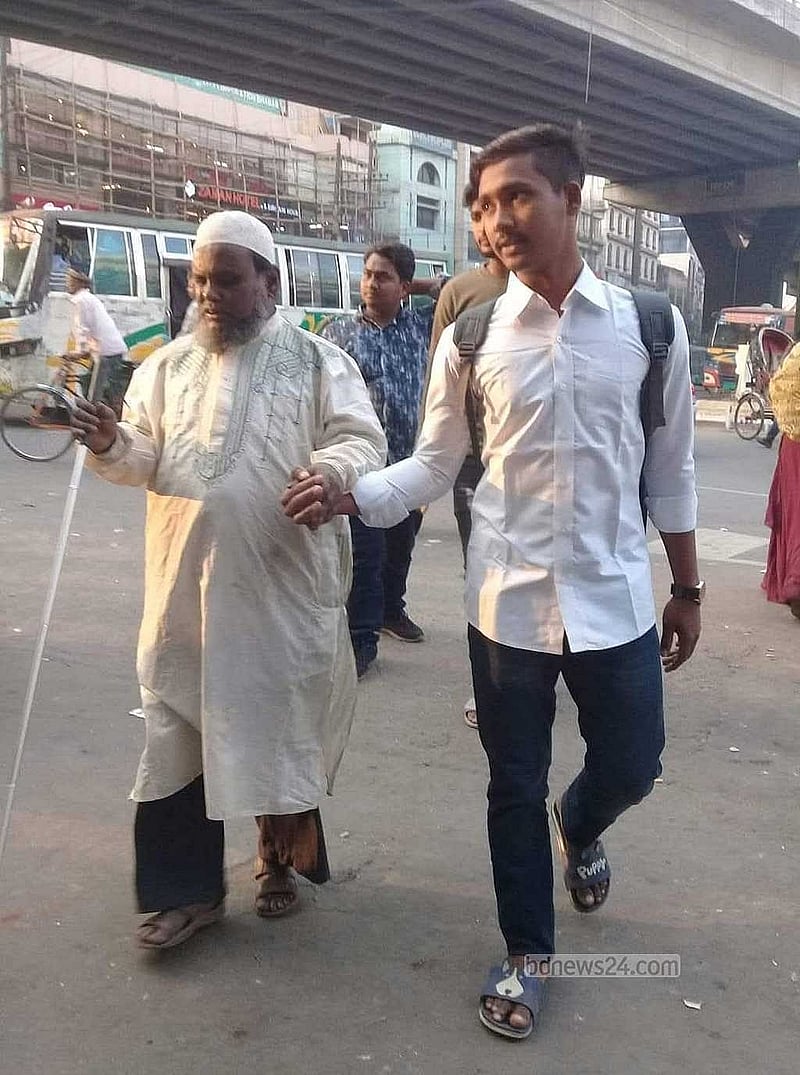একজন অন্ধ মানুষকে হাত ধরে রাস্তা পার করাচ্ছেন ওয়াসিম। 