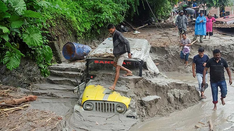 বন্যায় সড়ক ভেঙে তলিয়েছে গাড়ি। ছবি: রয়টার্স