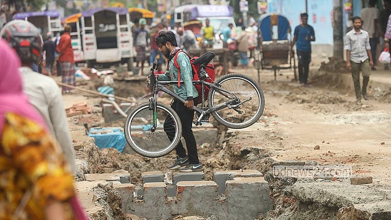রাজধানীর খিলগাঁও-বাসাবো সড়কে সুয়ারেজ লাইন সংস্কার কাজের জন্য খোঁড়া হয়েছে সড়ক, সাইকেল হাতে নিয়ে চলছেন এক ফুড ডেলিভারিম্যান