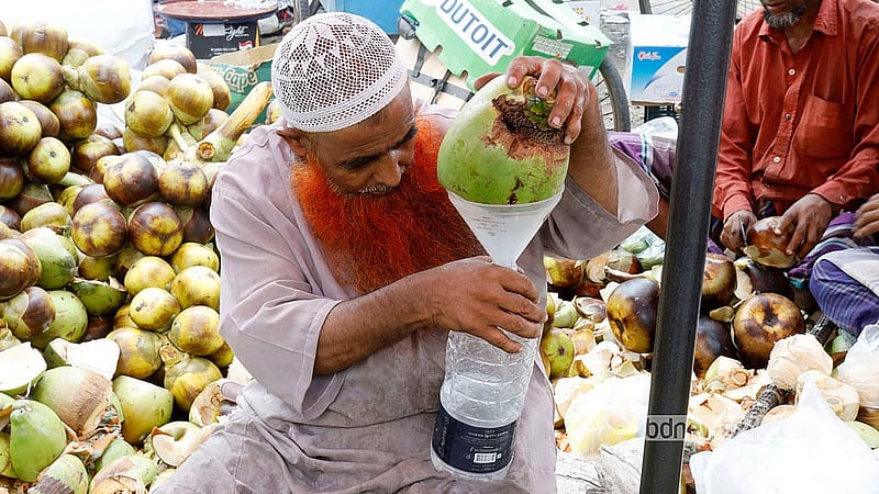 রাজধানীর কারওয়ান বাজারের একটি দোকানে বুধবার দুপুরে বোতলে ডাবের পানি ভরে নিচ্ছেন এক ক্রেতা