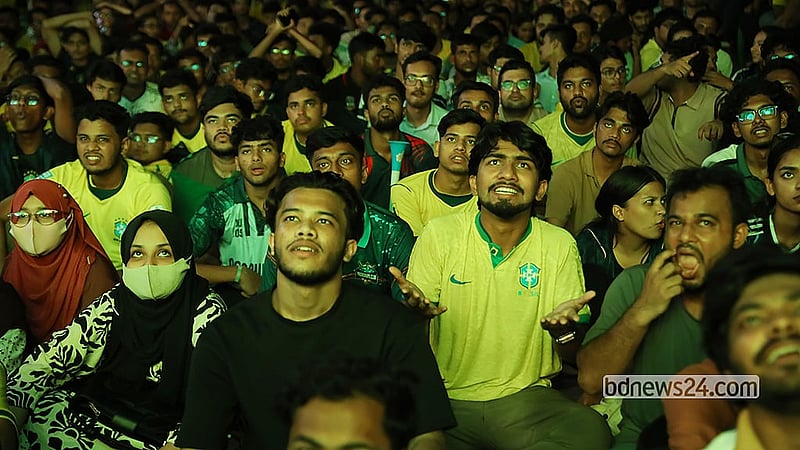 বড় পর্দায় ব্রাজিল-স্কটল্যান্ডের খেলা দেখতে বৃহস্পতিবার ভোরে ঢাকা বিশ্ববিদ্যালয়ের টিএসসি প্রাঙ্গণে সমর্থকদের উপচে পড়া ভিড়। বিশ্বকাপের ‘সি’ গ্রুপের ম্যাচে স্কটল্যান্ডকে ৩-০ গোলে হারায় ব্রাজিল