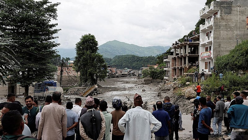 নেপালের নুয়াকোট জেলার ত্রিশুলিতে বুধবার হড়পা বানের পর কাদায় ঢেকে যাওয়া ঘরবাড়ি ও রাস্তার পাশে দাঁড়িয়ে স্থানীয় বাসিন্দারা। ছবি: রয়টার্স।