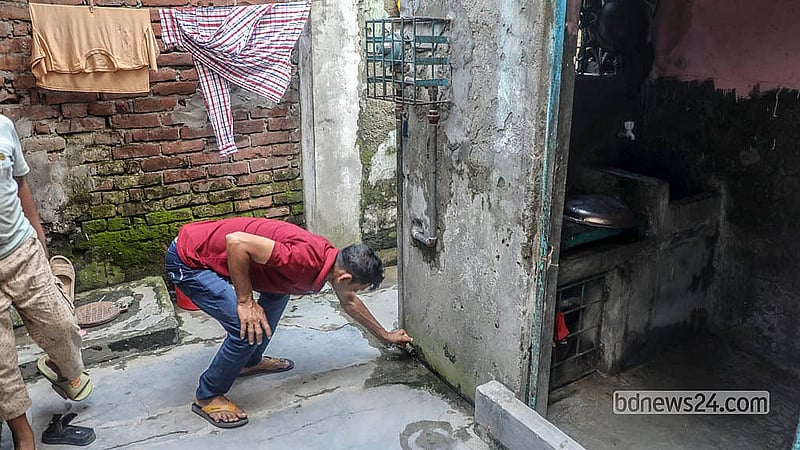 ঢাকার জুরাইনে ‘বিড়ি ফ্যাক্টরির’ গলিতে তিতাস গ্যাসের পাইপ থেকে জমে যাওয়া পানি বের করছেন একজন