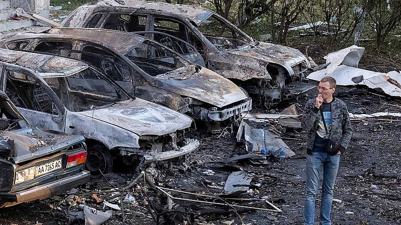 রাশিয়ার ক্ষেপণাস্ত্র হামলায় পুড়ে যাওয়া গাড়িগুলোর কাছে স্থানীয় এক বাসিন্দা। ছবি: রয়টার্স 
