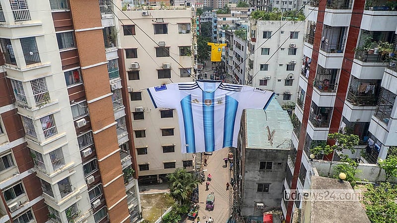 রাজধানীর মিরপুরের ইব্রাহীমপুর এলাকায় বহুতল দুই ভবনের সঙ্গে দড়ি দিয়ে ঝোলানো হয়েছে আর্জেন্টিনা ফুটবল দলের ৪০/৩০ ফুটের জার্সি। এটি বানাতে ৫০ হাজার টাকা খরচ হওয়ার কথা বলছেন সমর্থকরা