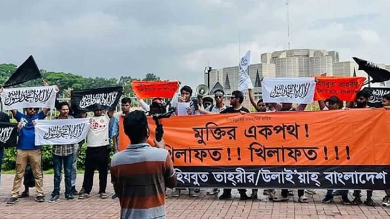 ২০২৪ সালের ৫ অগাস্ট অভ্যুত্থানে আওয়ামী লীগ সরকারের পতনের পর ৭ অগাস্ট জাতীয় সংসদের সামনে হিযবুত তাহরীরের মিছিলে কালেমা লেখা পতাকা দেখানো হয়। ছবি: বিবিসি বাংলা