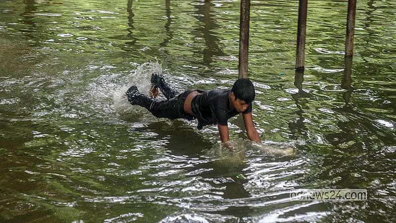 টানা বৃষ্টির কারণে ধানমন্ডি লেকের উপচে পড়া পানিতে খেলায় মেতেছে এক শিশু