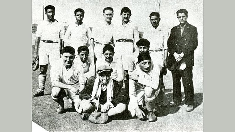 সামনের সারিতে, মাথায় টুপি আর গলায় স্কার্ফ জড়িয়ে বসে আছেন কাম্যু।