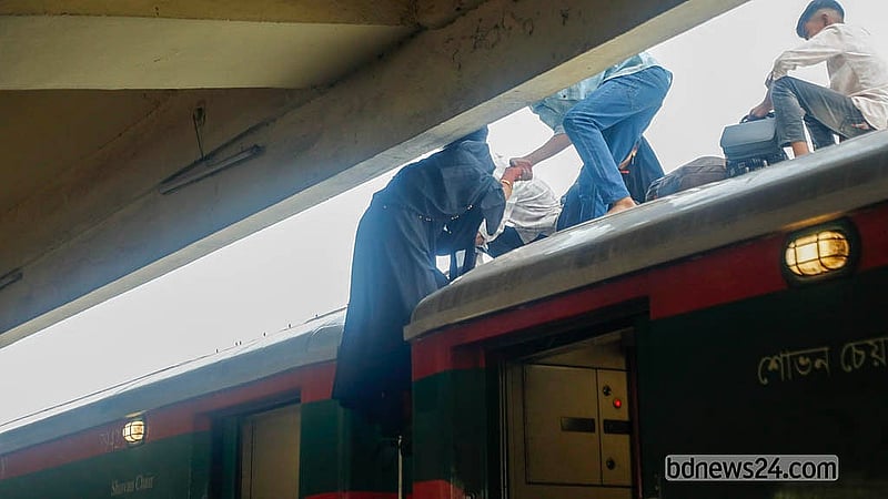 ভেতরে জায়গা নেই; বাড়িতো যেতে হবে। কমলাপুর স্টেশনে ট্রেনের ছাদে উঠছেন এক নারী