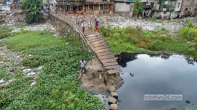রাজধানীর কামরাঙ্গীরচরের রসুলপুর এলাকায় আদি বুড়িগঙ্গা চ্যানেলের ওপর ভাঙা সাঁকো দিয়ে পারাপার হচ্ছে মানুষ