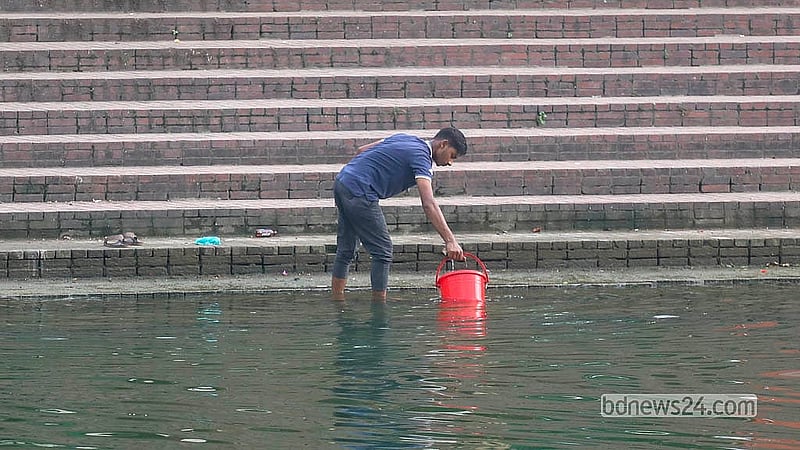 ক্রিসেন্ট লেক থেকে বালতি ভরে পানি নিয়ে যাচ্ছে চায়ের এক দোকানি। দূষিত এ পানি ব্যবহার করা হচ্ছে নানা কাজে