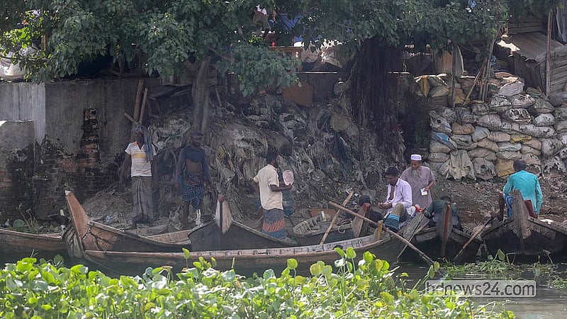 তীব্র রোদ থেকে সুরক্ষা পেতে ছাতা মাথায় যাত্রীর অপেক্ষায় পুরান ঢাকার সোয়ারীঘাটের খেয়া নৌকার মাঝিরা