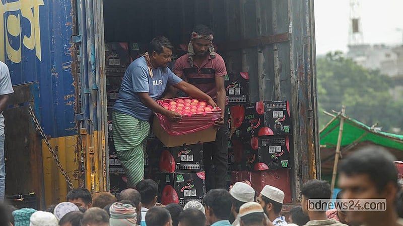 রাজধানীর বাদামতলী ফলের আড়তে নিলামে আপেলের দাম হাঁকাচ্ছেন এক আড়তদার