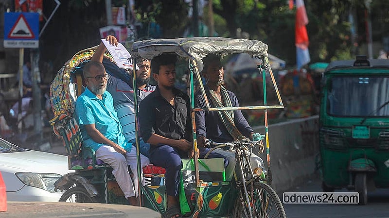 ঢাকা বিশ্ববিদ্যালয় এলাকায় শনিবার তীব্র রোদ থেকে সুরক্ষা দিতে পাশের যাত্রীর মাথার উপরে ফাইল ধরে রেখেছেন এক ব্যক্তি