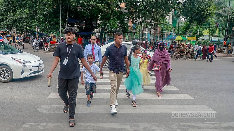 ঢাকার মানিক মিয়া এভিনিউয়ে বুধবার দুপুরে পথচারীদের রাস্তা পারাপারে সাহায্য করছেন শিক্ষার্থীরা