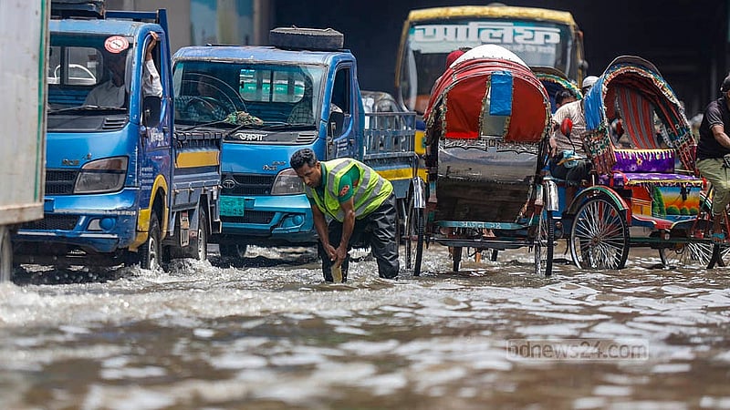মিরপুরে রোববার সকালে টানা বৃষ্টিতে তলিয়ে যাওয়া সড়কের পানি সরছিল না। সিটি করপোরেশনের কর্মীরা তাই ম্যানহোলের ঢাকনায় আটকা আবর্জনা পরিষ্কার করছিলেন।