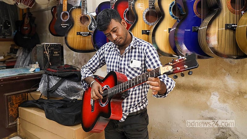 পুরান ঢাকার শাঁখারীবাজারের একটি দোকান থেকে গিটার কিনে তা পরখ করে দেখছেন এক ক্রেতা