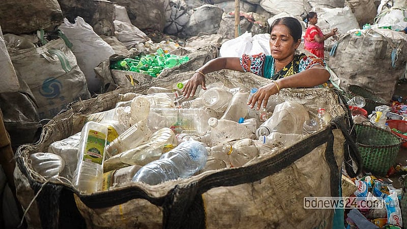 রাজধানীর হাজারীবাগের এক প্লাস্টিক রিসাইকেল কারখানায় বিভিন্ন রঙের বোতল বাছাই করছেন এক শ্রমিক