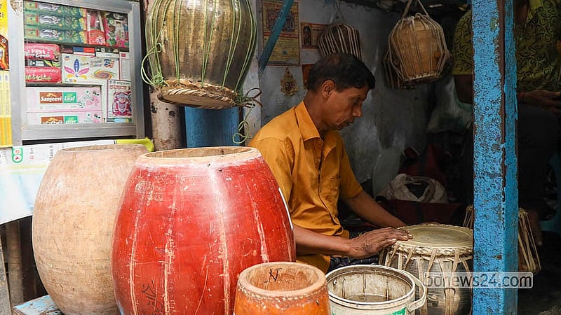 পুরান ঢাকার শাঁখারীবাজারের দোকানে সাজিয়ে রাখা বড় বড় ঢাক ও ঢোলের মাঝে বসে তবলার টিউনিং ও চামড়া পরখ করছেন কারিগর