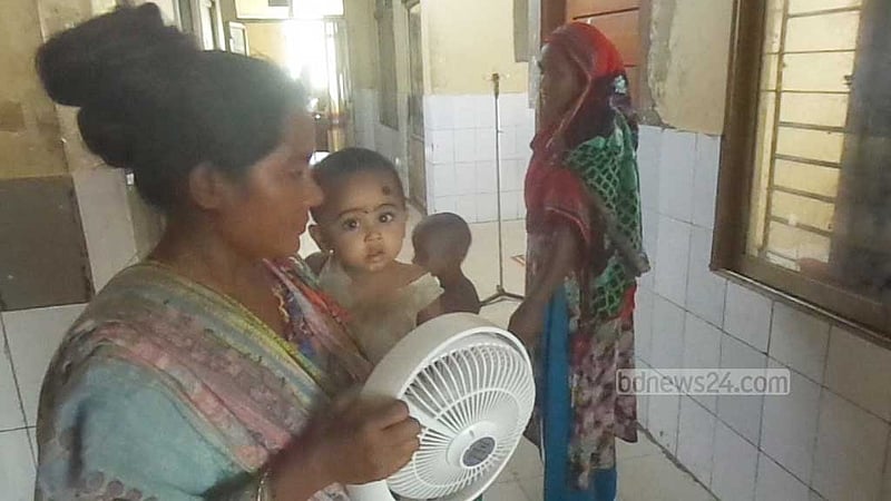 হাসপাতালের ডায়রিয়া ওয়ার্ডের ফ্যান না থাকায় অসুস্থ সন্তানকে রিচার্জেবল ফ্যান দিয়ে বাতাস দিচ্ছেন এক মা।