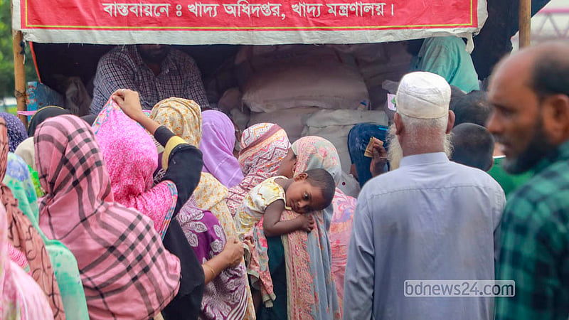 সাশ্রয়ী মূল্যে চাল ও আটা কিনতে ‘ওএমএস ট্রাকসেলে’ সন্তান কোলে অপেক্ষা করছেন এক নারী। &amp;nbsp;&amp;nbsp;ছবি: আব্দুল্লাহ আল মমীন