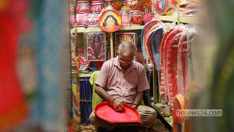 আসন্ন দুর্গাপূজা উপলক্ষে পুরান ঢাকার শাঁখারিবাজারে বেড়েছে ব্যস্ততা। উৎসবের অনুষঙ্গ হিসেবে একটি দোকানে বসে ডালা, কুলাসহ পূজার বিভিন্ন উপকরণ রাঙিয়ে তুলছেন একজন কারিগর। ছবি: শামছুল হক রিপন