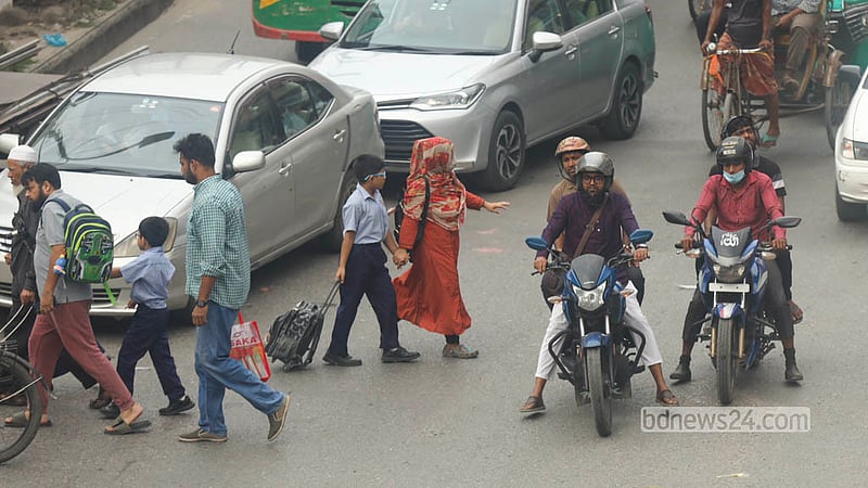 রাজধানীর মালিবাগে হাতের ইশারায় গাড়ি থামিয়ে সন্তানকে নিয়ে রাস্তা পার হচ্ছেন এক অভিভাবক। ছবি: শামছুল হক রিপন