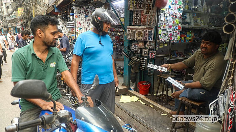 রাজধানীর বংশাল এলাকায় এক দোকানি বাইকারকে নম্বর প্লেট দেখাচ্ছেন।&amp;nbsp;&amp;nbsp; ছবি: আব্দুল্লাহ আল মমীন
