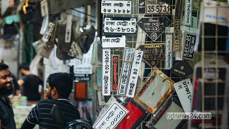 দোকানে সাজানো মোটরসাইকেলের সামনের অংশের বিভিন্ন ধরন ও মানের নম্বর প্লেট। রাজধানীর বংশাল এলাকায় এসব নম্বর প্লেট মিলছে ১৫০ থেকে ৫০০ টাকায়।&amp;nbsp;&amp;nbsp; ছবি: আব্দুল্লাহ আল মমীন