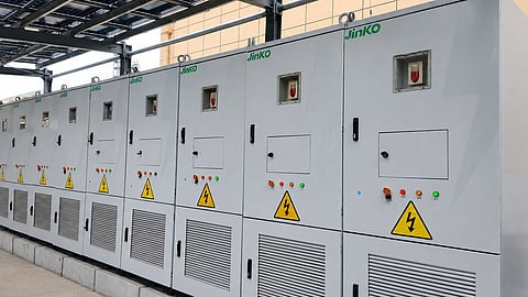 Rows of grey SunGiga battery storage cabinets with Jinko branding beneath a rooftop solar canopy at the Binzhou C&I storage site.