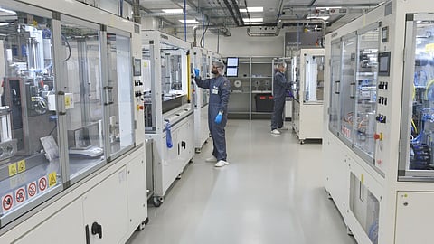 Two researchers in cleanroom suits work at the semi-automated pouch cell production line in the dry room of the Fraunhofer ISE Battery Materials and Cell Production Lab, where the thick-film electrode prototypes were built.