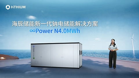 A speaker beside a white battery storage container on a launch-event stage.