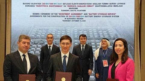 Six officials, three holding signed folders, before a banner for the 250 MW Bukhara BESS.