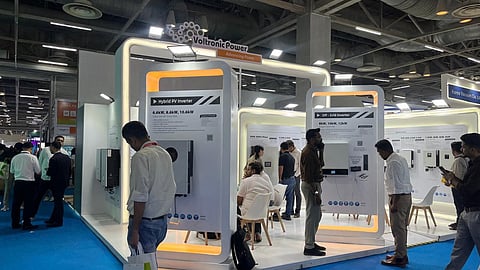 Voltronic Power stand at REI Expo 2026 with orange-lit display arches, wall-mounted inverters and visitors.